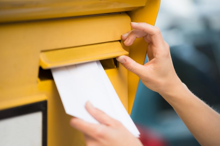 Closeup,Of,Woman's,Hands,Inserting,Letter,In,Mailbox